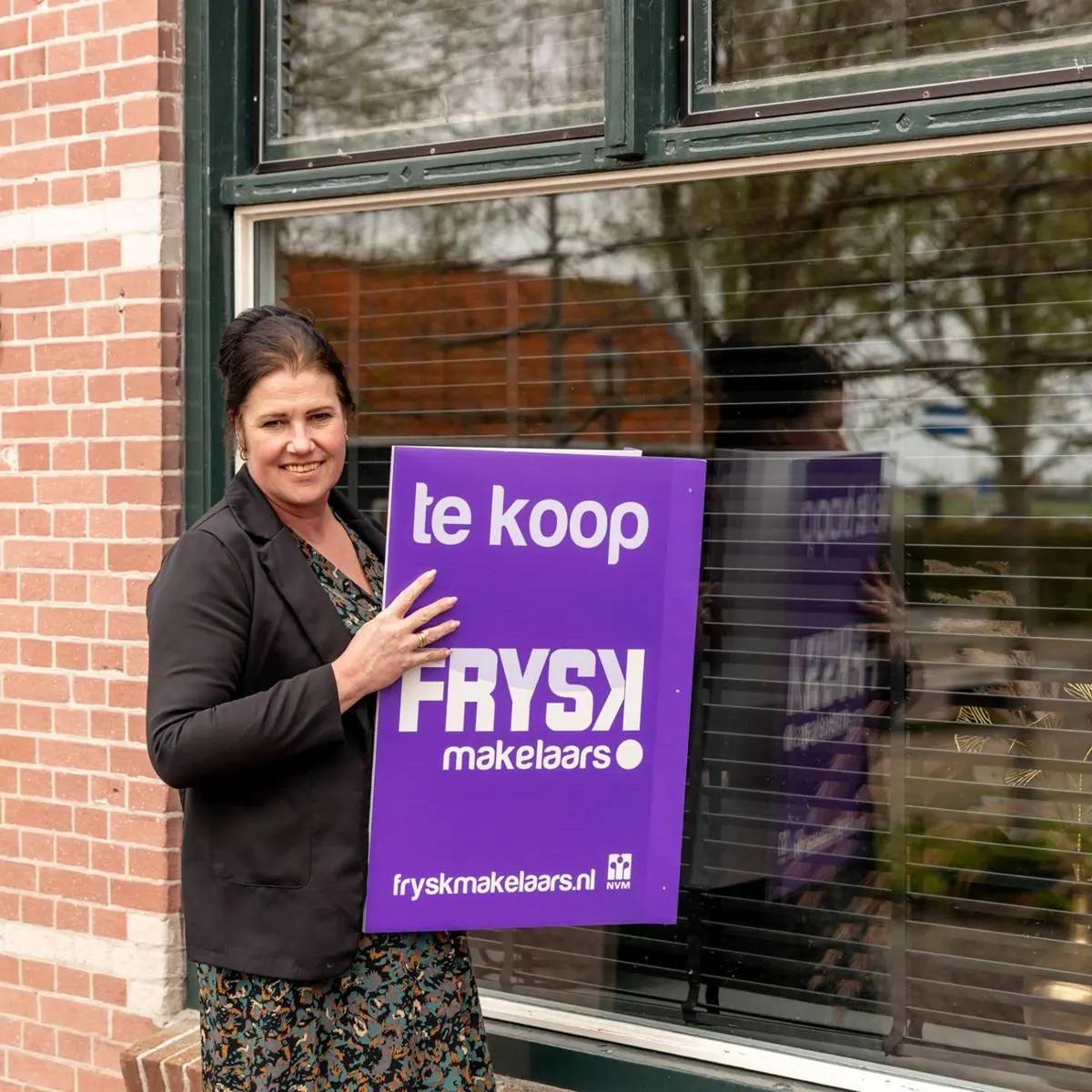 Makelaar van FRYSK met een te-koop-bord voor een woning